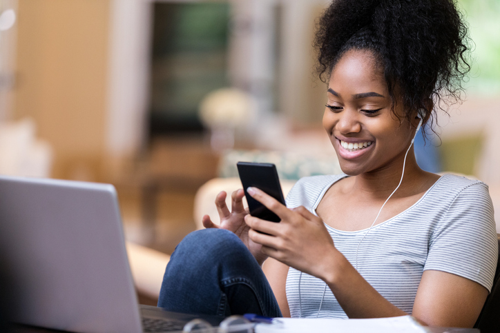 A woman focused on her smartphone, typing a message with a smile, staying connected with friends or loved ones.